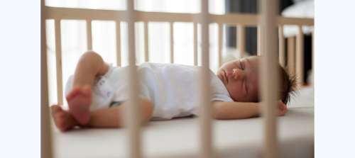Newborn sleeping soundly in crib. White noise can help babies sleep.