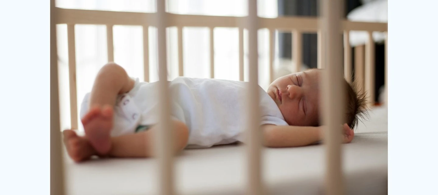 Newborn sleeping soundly in crib. White noise can help babies sleep. | Huckleberry