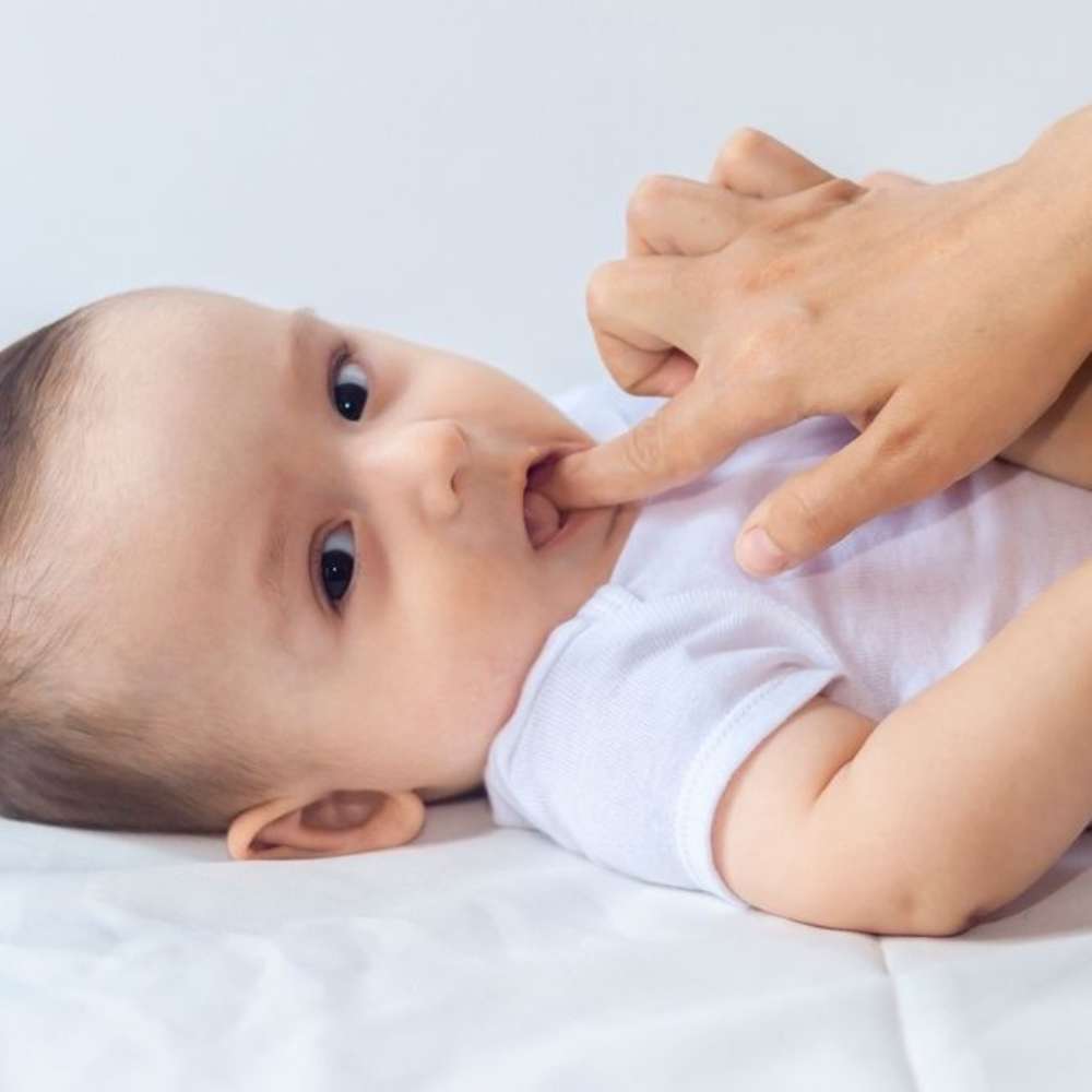 Mother using finger to massage teething baby's gums.