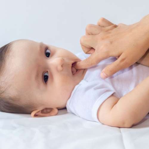 Mother using finger to massage teething baby's gums.