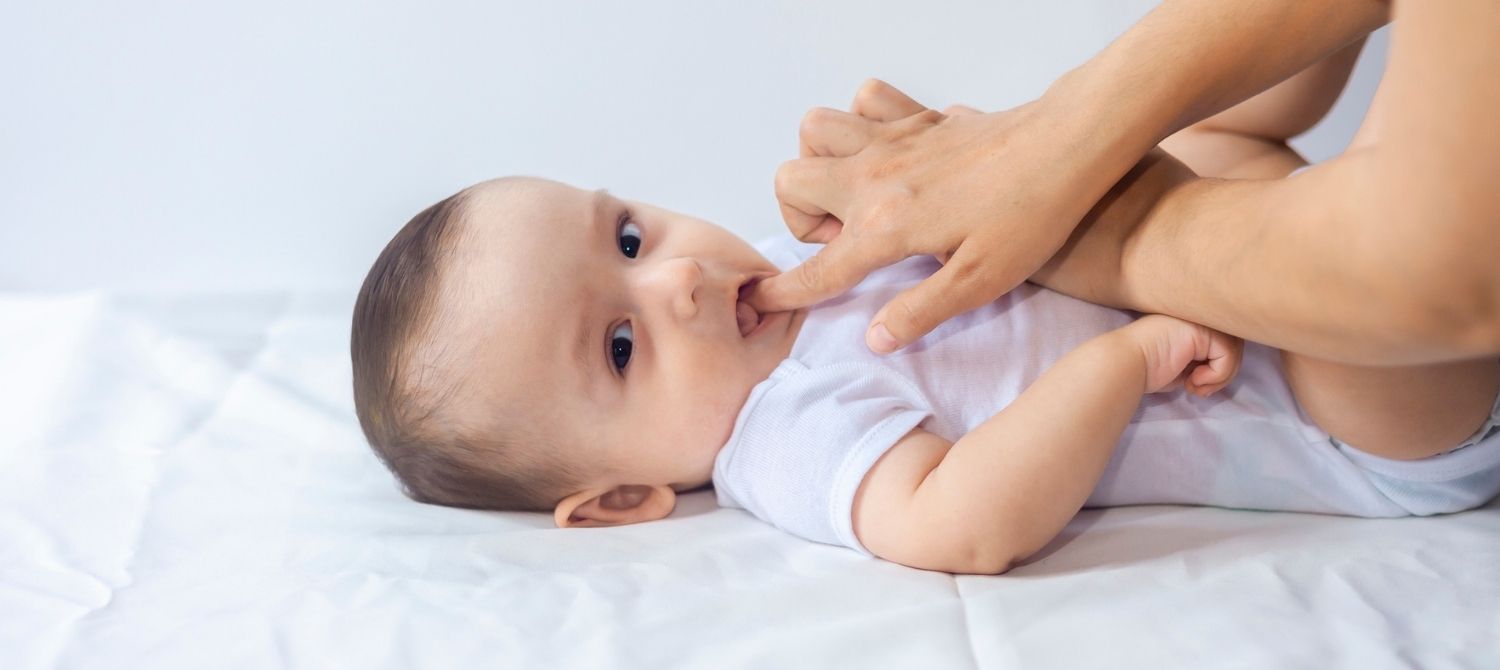 Mother using finger to massage teething baby's gums.