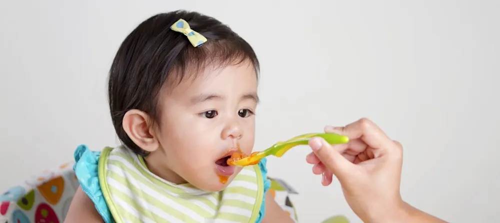 Baby eating beans safely being fed through baby led weaning