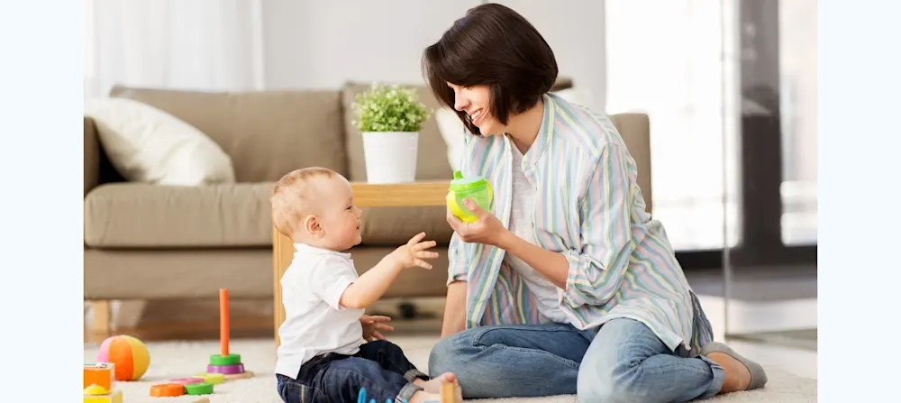 Mother offering 1 year old child a sippy cup