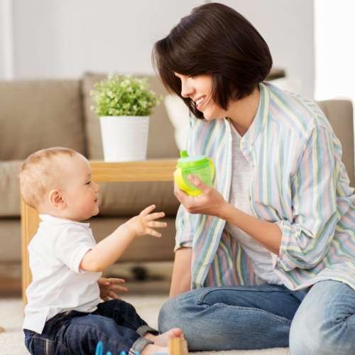 Mother offering 1 year old child a sippy cup