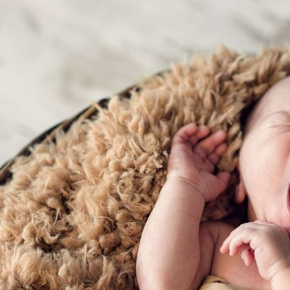 Yawning newborn on furry brown blanket