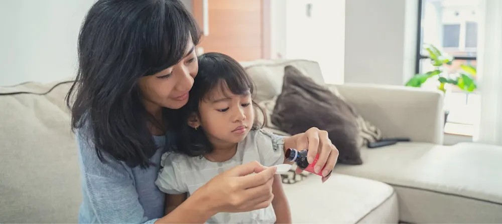 A mother giving her child medicine.