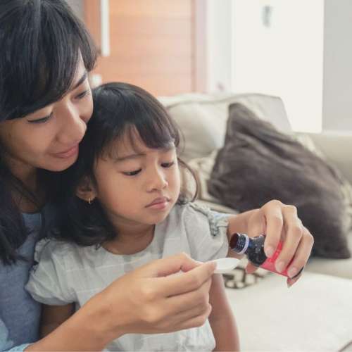 A mother giving her child medicine.