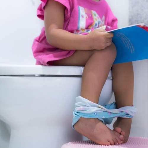 Toddler reading book while sitting on potty