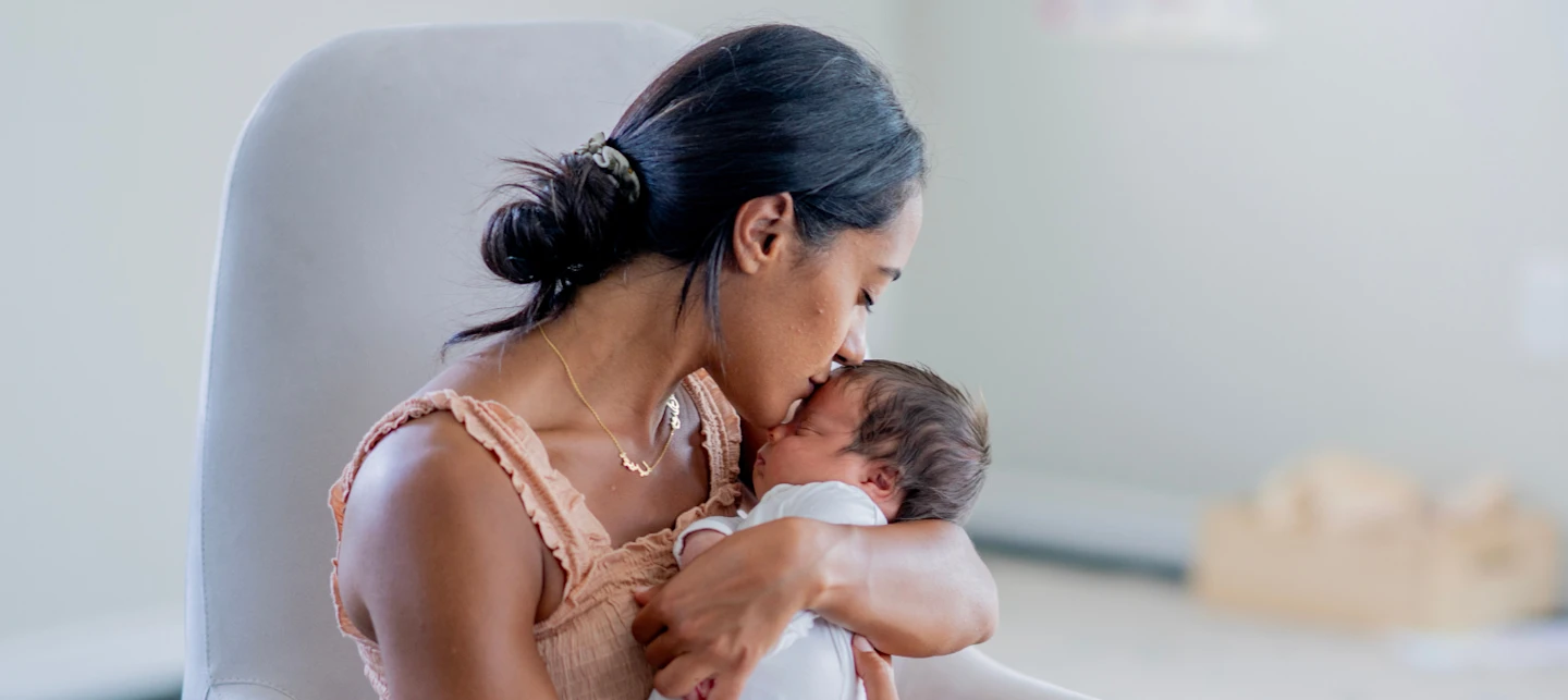 Newborn baby sleeping in mother's arms. | Huckleberry