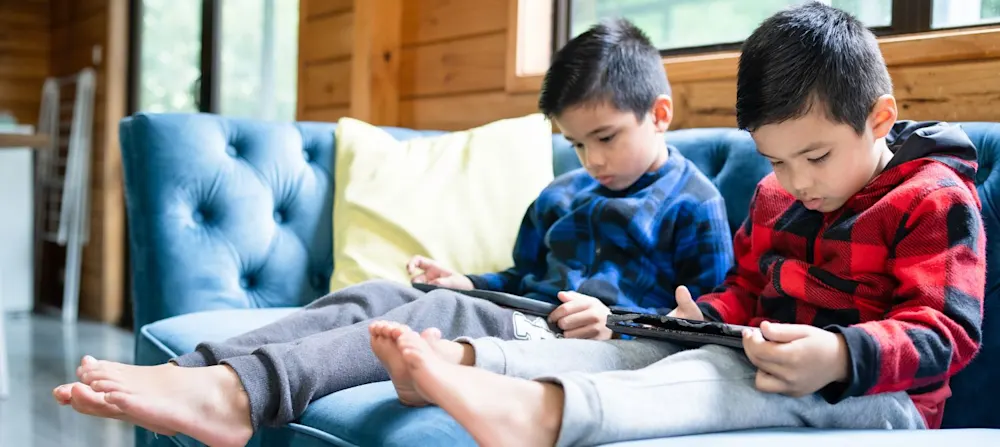 Two young boys playing on their tablets.