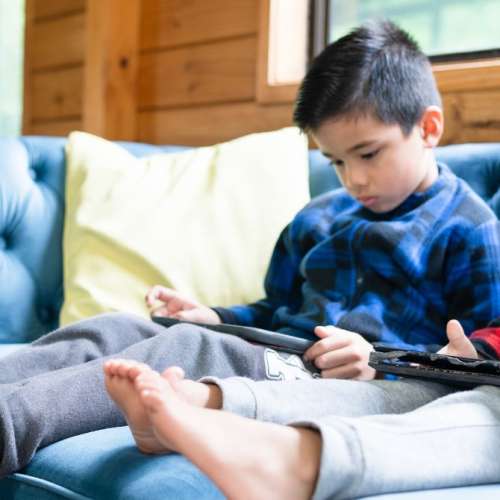 Two young boys playing on their tablets.