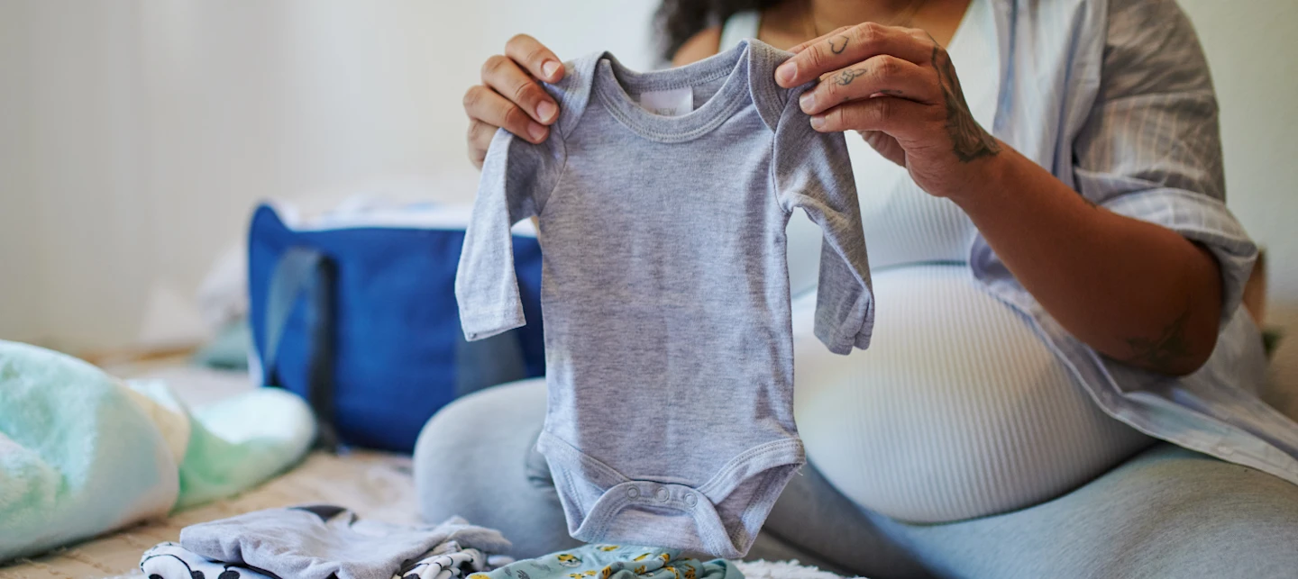 Pregnant mom looking at newborn clothing | Huckleberry