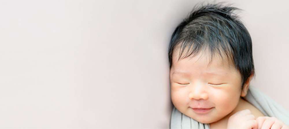 A baby sleeping and smiling while sleeping. 