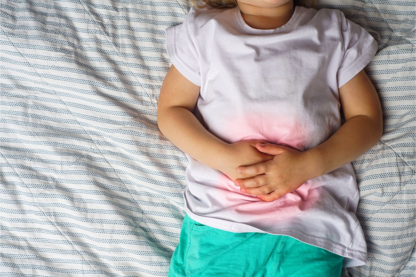 Toddler holding stomach while lying down