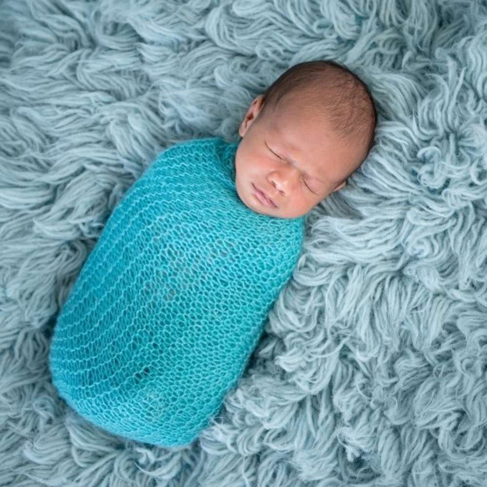 A baby swaddled in a blue blanket.