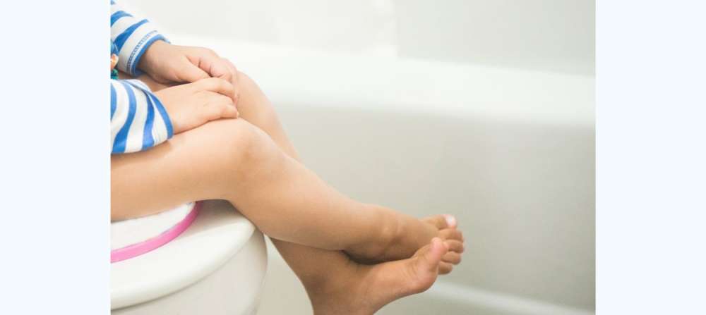 Toddler sitting on potty with legs crossed