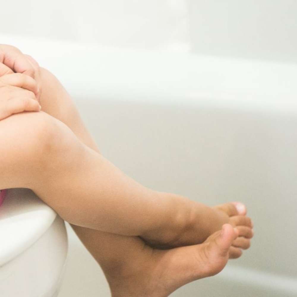 Toddler sitting on potty with legs crossed