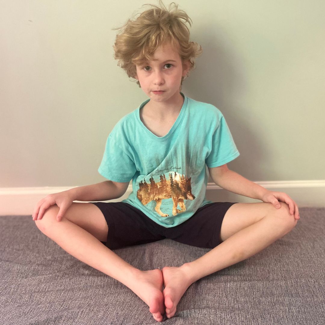A child doing a butterfly yoga pose.