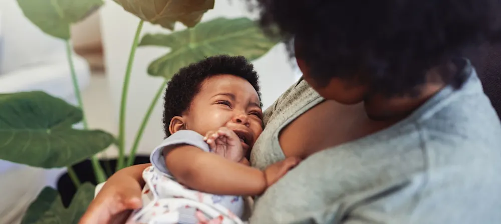 A woman is holding a crying baby.