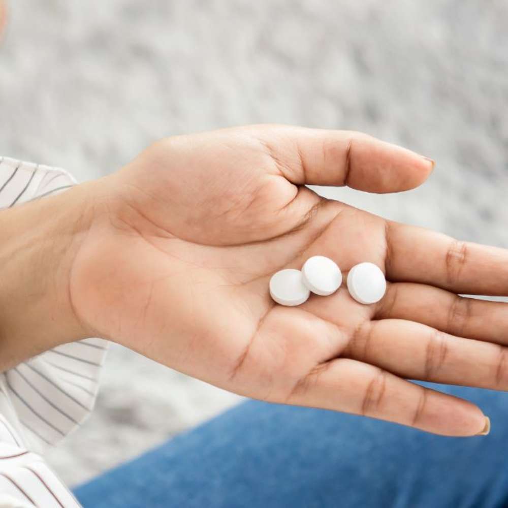 A woman looking at melatonin pills in her hand. 