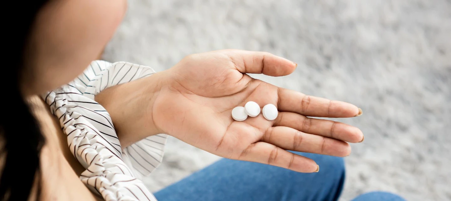 A woman looking at melatonin pills in her hand. | Huckleberry