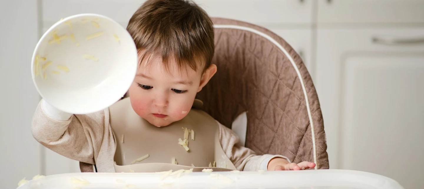 A child throwing food in their high chair. | Huckleberry