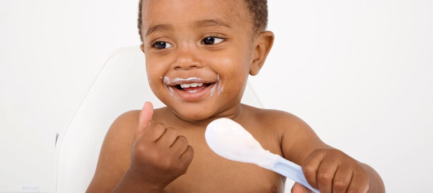A baby eating from a spoon. | Huckleberry