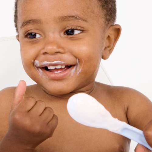 A baby eating from a spoon.