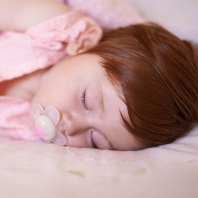 Toddler sleeping with a pacifier and blanket for a nap