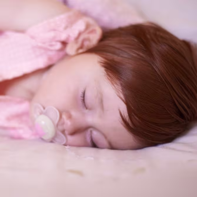 Toddler sleeping with a pacifier and blanket for a nap