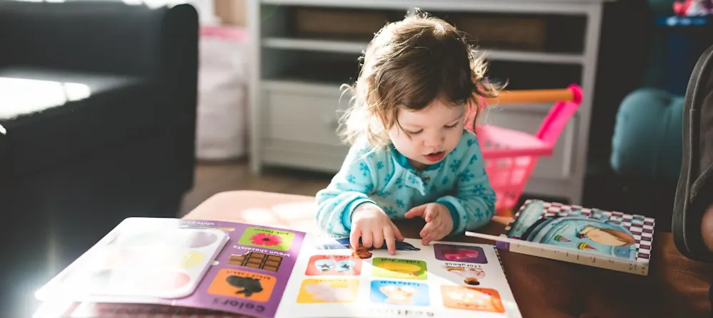 A toddler looking at a book.