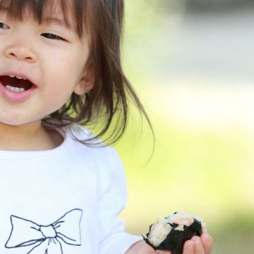 A child is smiling while holding food.