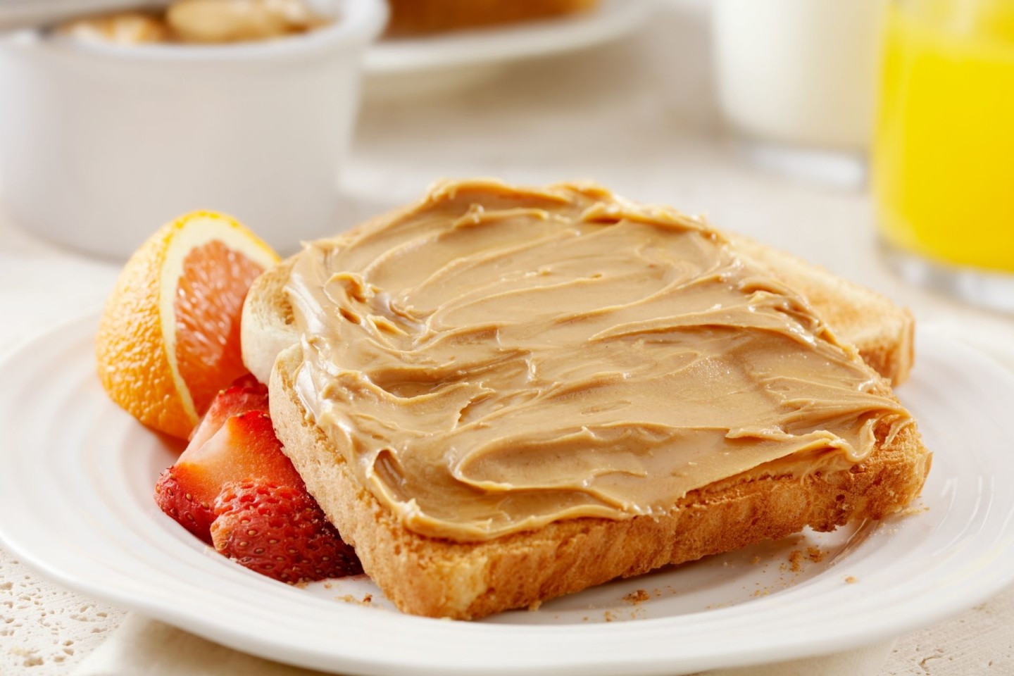 Peanut butter on toast with fruit, orange juice, and milk.