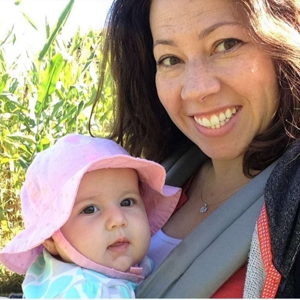 Amber holds her second baby in a front carrier.