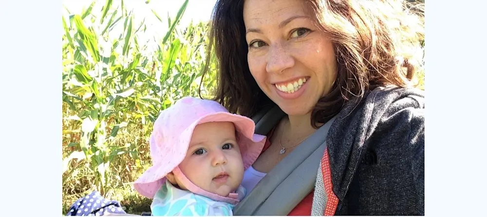 Amber holds her second baby in a front carrier.