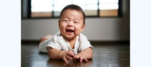 Smiling 8 month old baby on tummy on floor
