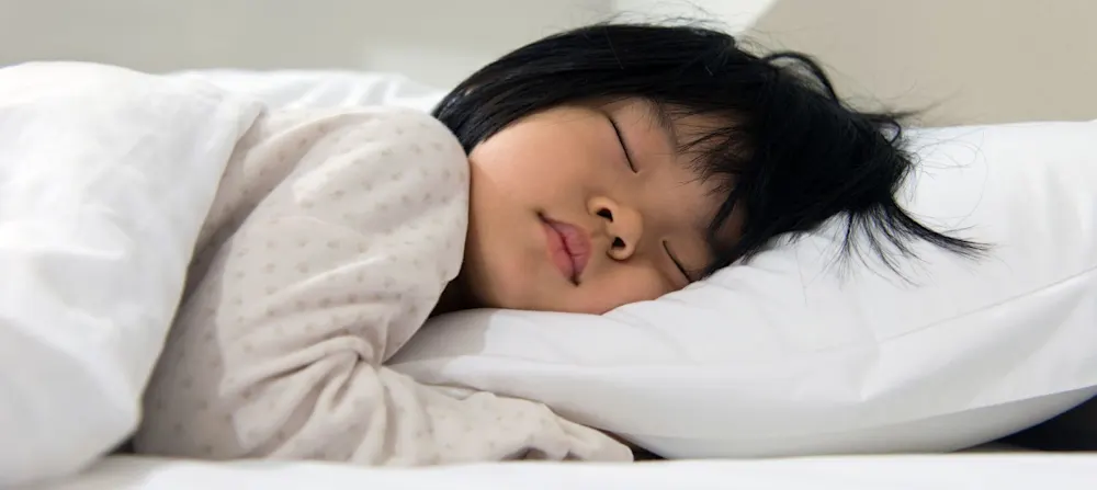A toddler sleeping with a pillow.