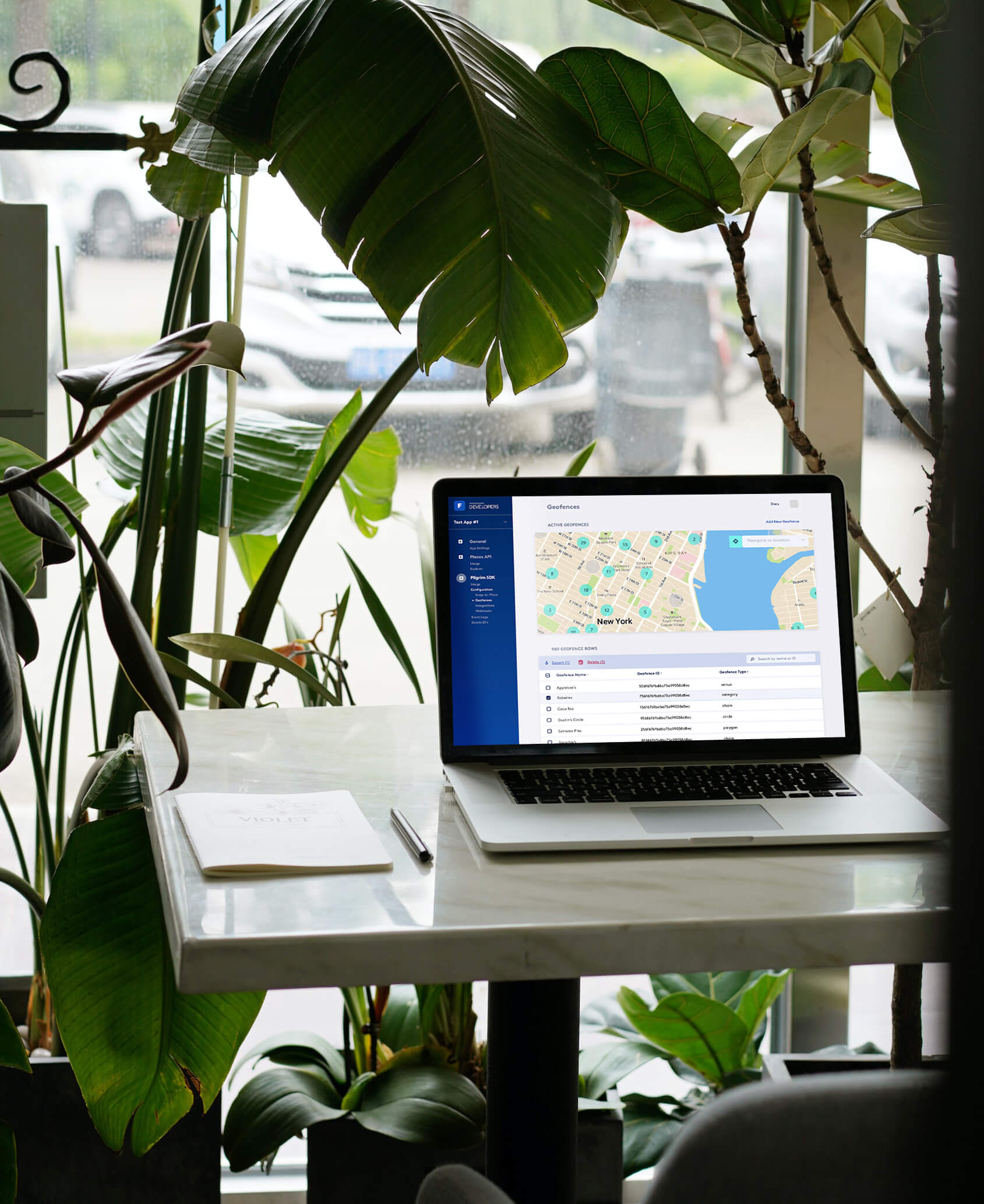 A laptop open to the geofence dashboard sitting on a desk with many plants around it.