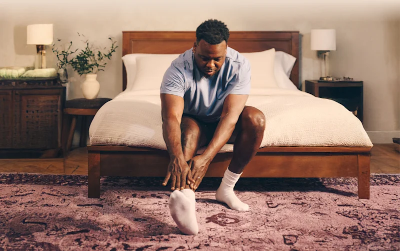 Man stretching legs sitting on bed