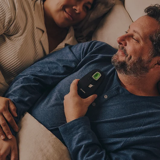 Man and women laying in bed. Man using Inspire therapy remote