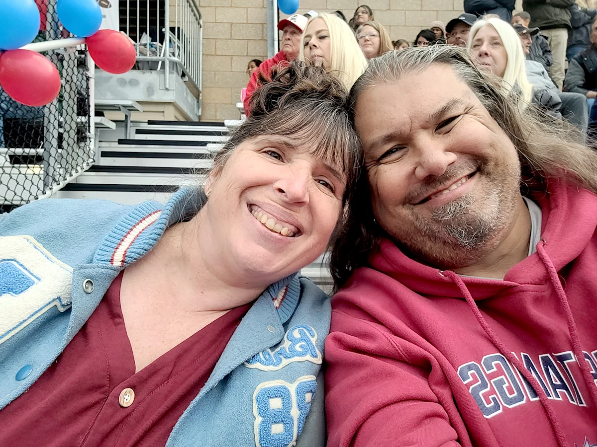 Bret Holmes and his wife Janece sit in the bleachers during a sporting event.