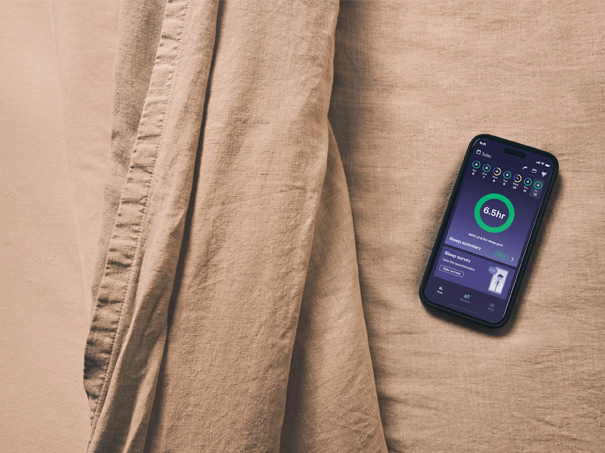 Inspire Sleep mobile app showing sleep tracking dashboard with 6.5-hour sleep summary on a smartphone against linen background