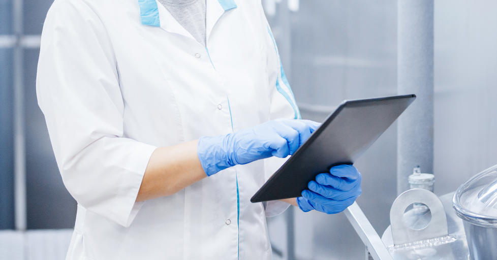 Factory worker inspecting production line tanker in of dairy factory with computer tablet