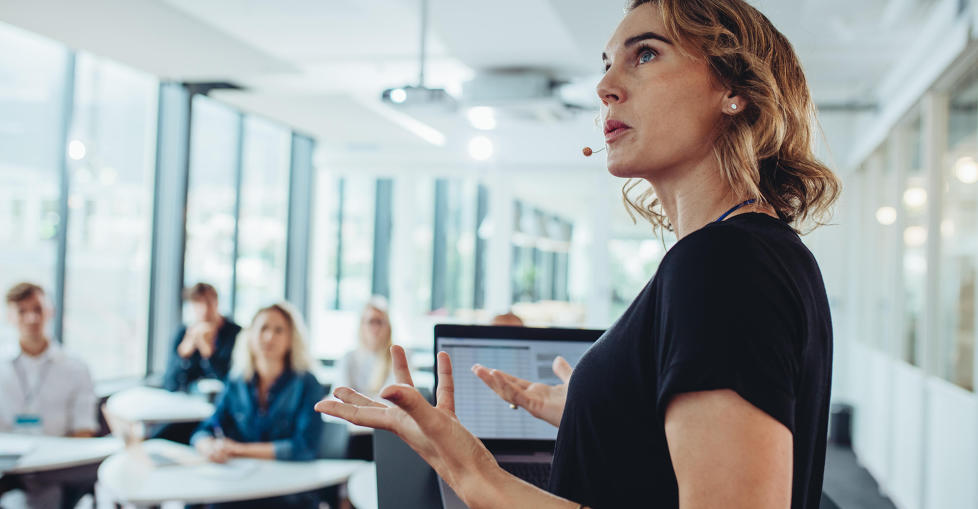 Female food and product safety expert delivering training standing up at the front of a class where a mixed group of people are sitting