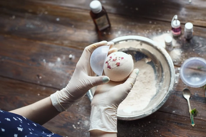 Person mit Handschuhen nimmt selbstgemachte Badekugel aus einer Form.