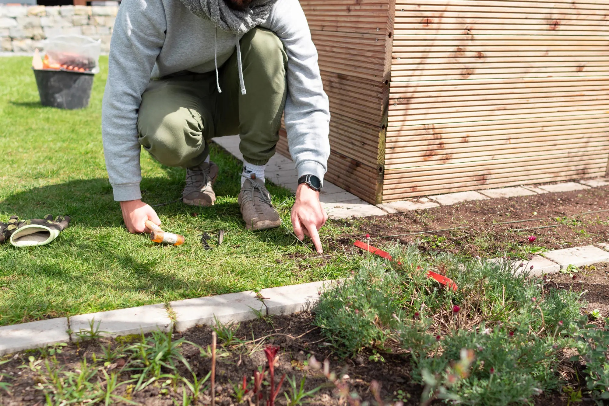 Ein Mann verlegt Kabel für Rasenroboter im Garten