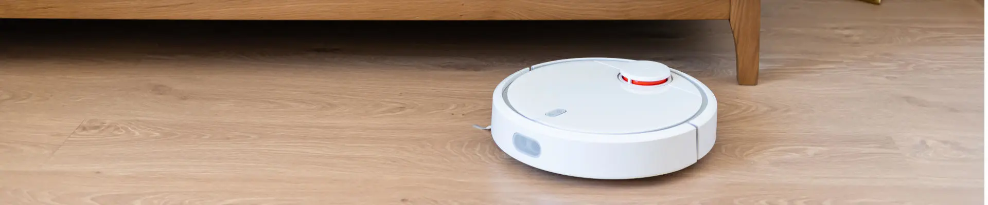 Schmuckbild: weißer Staubsauger-Roboter säubert Holzboden