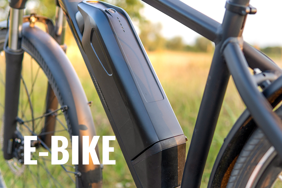 Werbung: Nahaufnahme des Akkus an einem E-Bike, das im Freien steht. Text-Overlay im Vordergrund: E-BIKE.