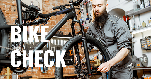 Werbung: Ein Mechaniker in einer Werkstatt überprüft ein Mountainbike. Text-Overlay im Vordergrund: Bike Check.