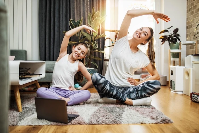 Mutter und Tochter sitzen im Schneidersitz auf dem Boden und machen Yogaübungen